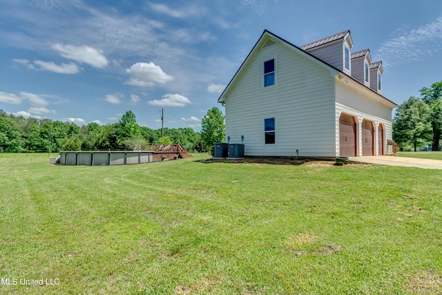 view of side of home featuring concrete driveway, a lawn, and an outdoor pool