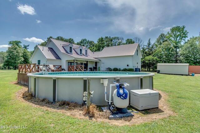 rear view of property featuring a lawn, metal roof, and an outdoor pool