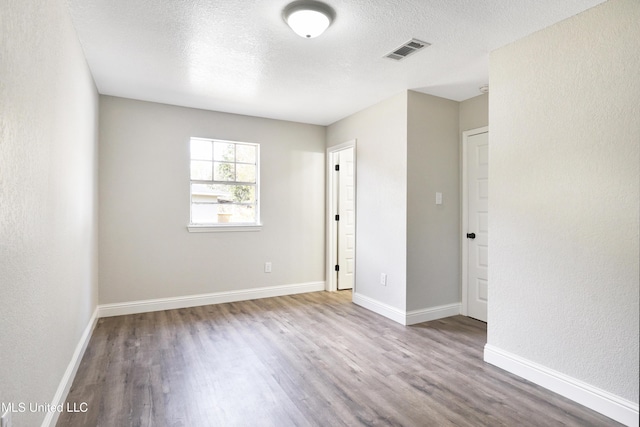 unfurnished room with wood-type flooring and a textured ceiling