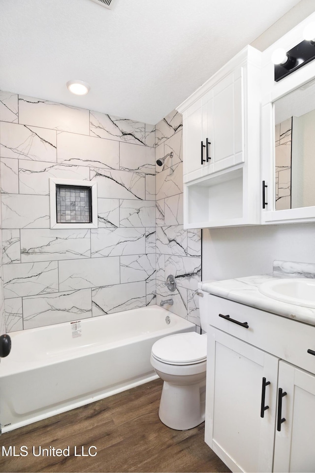 full bathroom with tiled shower / bath combo, wood-type flooring, vanity, and toilet