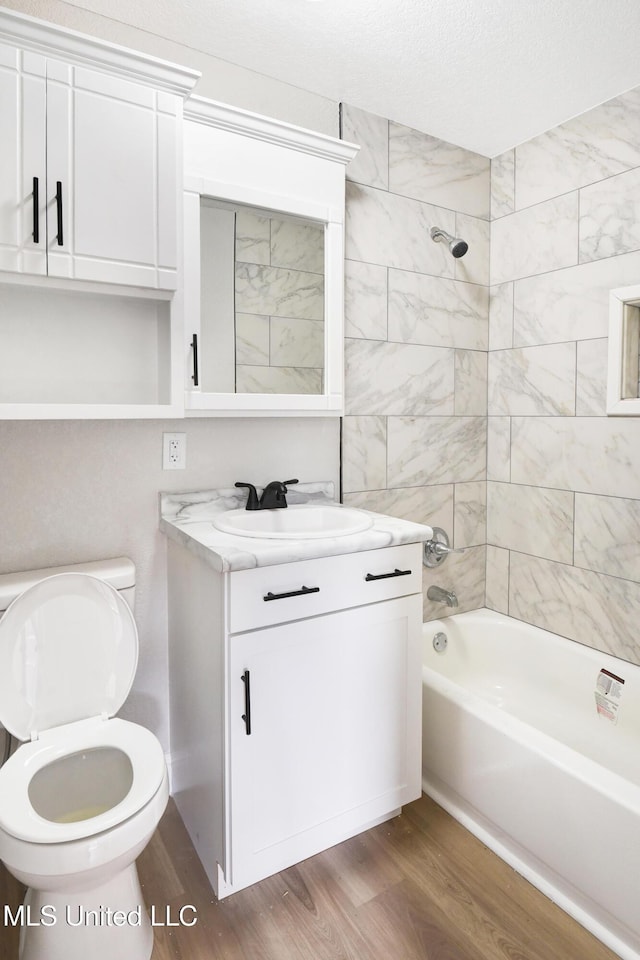 full bathroom with vanity, tiled shower / bath combo, wood-type flooring, and toilet