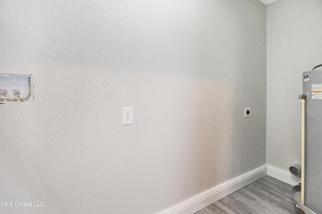 washroom with hookup for an electric dryer, hardwood / wood-style floors, and gas water heater