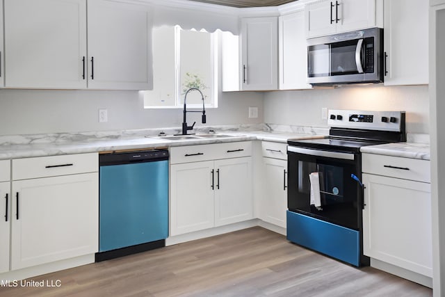 kitchen with white cabinetry, sink, light stone counters, light hardwood / wood-style floors, and stainless steel appliances