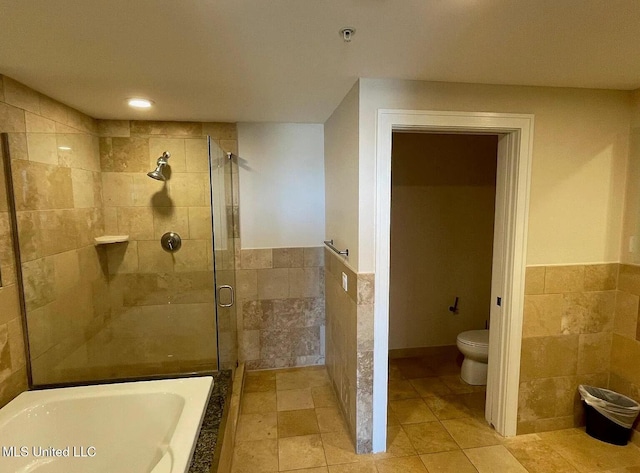 2060 Beach Blvd Unit 1206, Biloxi, MS 39531 - bathroom featuring a shower stall, tile walls, a bathtub, wainscoting, and tile patterned flooring