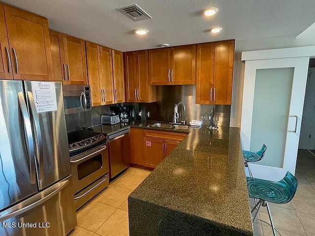 2060 Beach Blvd Unit 1206, Biloxi, MS 39531 - kitchen with appliances with stainless steel finishes, light tile patterned floors, brown cabinets, dark stone countertops, and recessed lighting