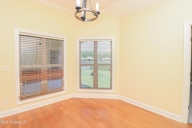 unfurnished dining area with light wood-style floors, ornamental molding, baseboards, and a chandelier