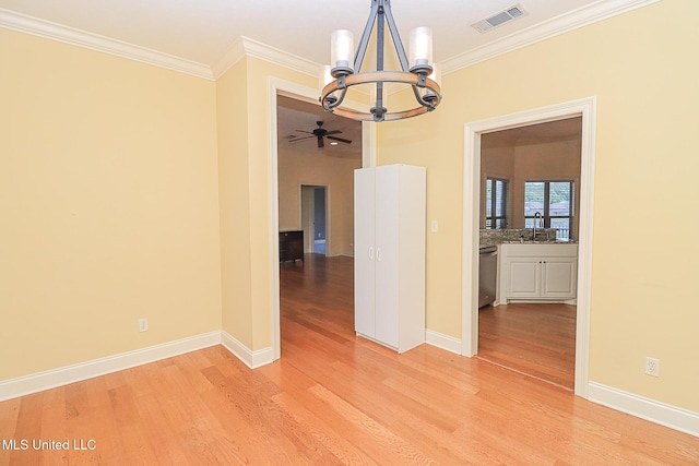 empty room with visible vents, ornamental molding, and light wood finished floors