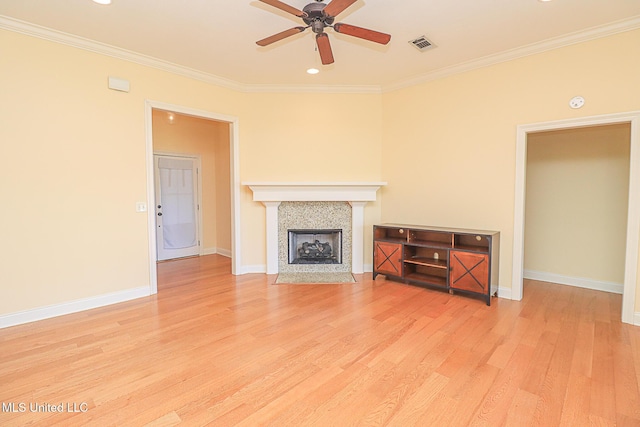 unfurnished living room with a ceiling fan, visible vents, a tiled fireplace, crown molding, and light wood-style flooring