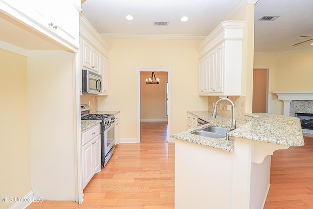 kitchen featuring a peninsula, appliances with stainless steel finishes, a sink, and visible vents