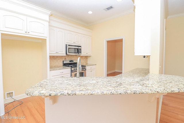 kitchen featuring visible vents, a peninsula, appliances with stainless steel finishes, and a kitchen bar