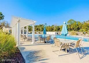 view of patio / terrace featuring a community pool, a pergola, and outdoor dining space