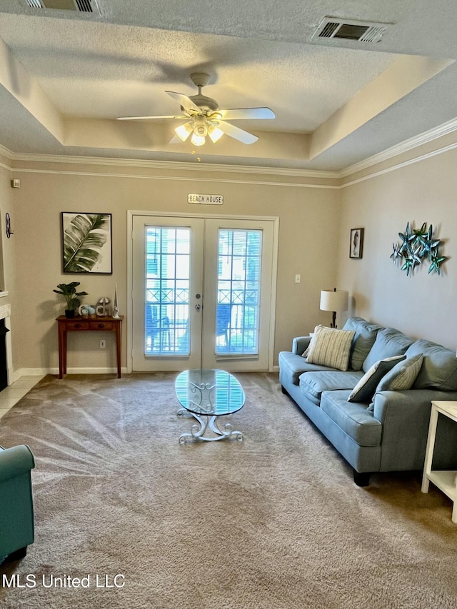 carpeted living room featuring crown molding, a textured ceiling, and a tray ceiling