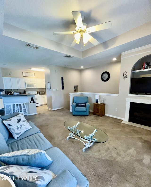 living room with ceiling fan, visible vents, light carpet, and baseboards