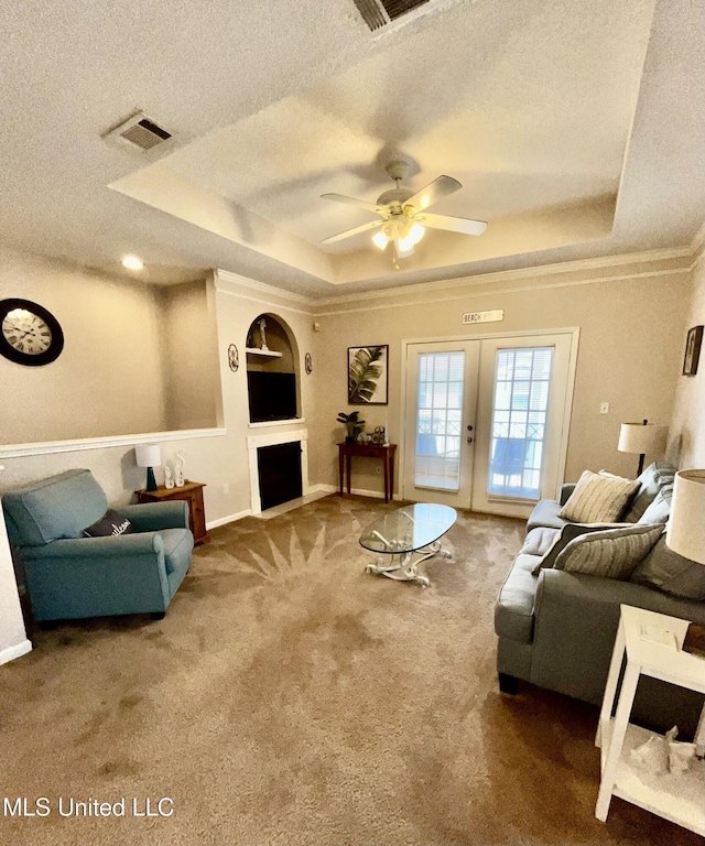 carpeted living area with a textured ceiling, a tray ceiling, visible vents, and french doors