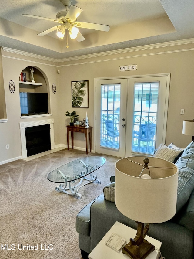 carpeted living room with crown molding, built in features, a ceiling fan, and french doors