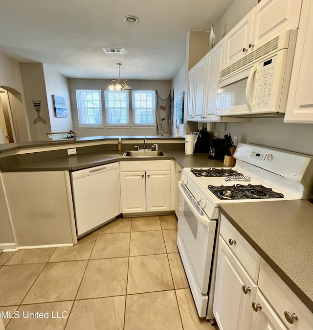 kitchen featuring visible vents, a peninsula, dark countertops, white appliances, and a sink
