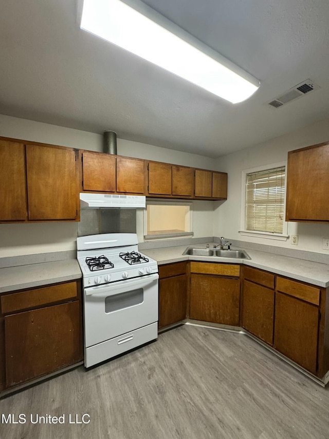 kitchen with light wood-type flooring, sink, and white range with gas cooktop