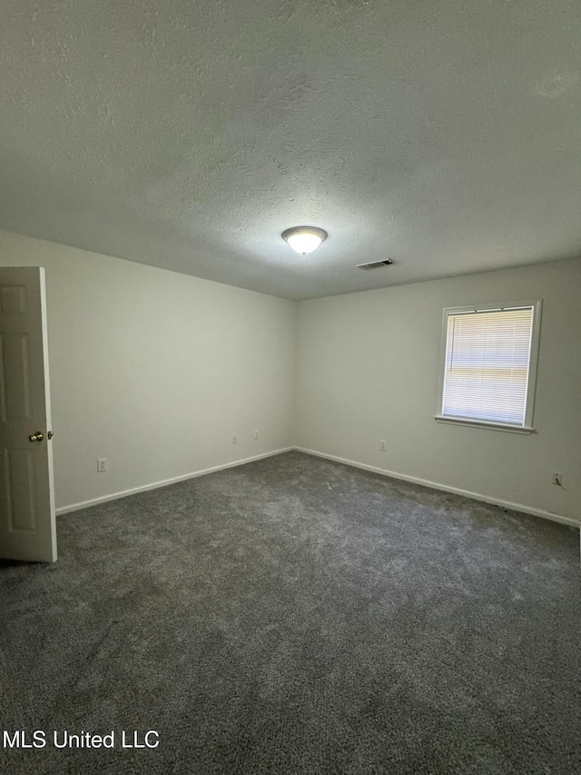 carpeted empty room featuring a textured ceiling