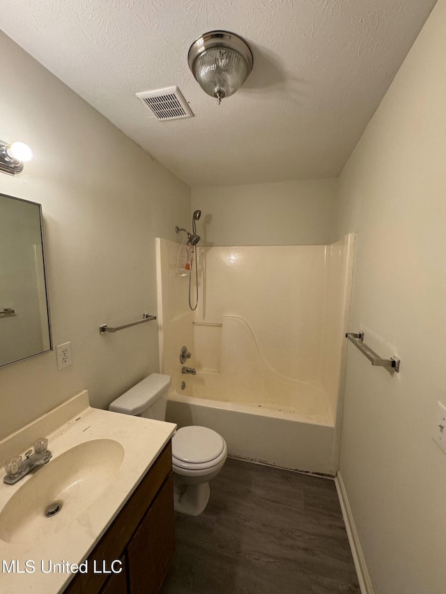 full bathroom featuring bathtub / shower combination, vanity, a textured ceiling, hardwood / wood-style flooring, and toilet