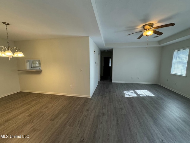 unfurnished living room featuring a raised ceiling, ceiling fan with notable chandelier, and dark hardwood / wood-style floors