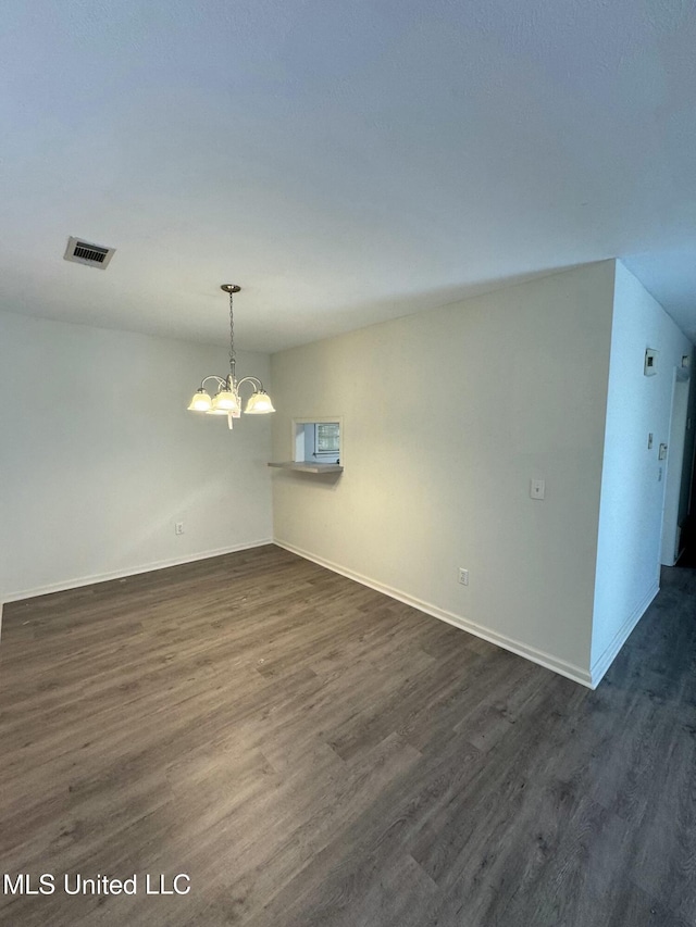 empty room with a chandelier and dark hardwood / wood-style floors