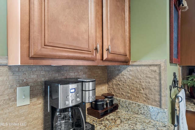 9476 Plantation Rd, Olive Branch, MS 38654 - interior details featuring tasteful backsplash, brown cabinetry, and light stone countertops