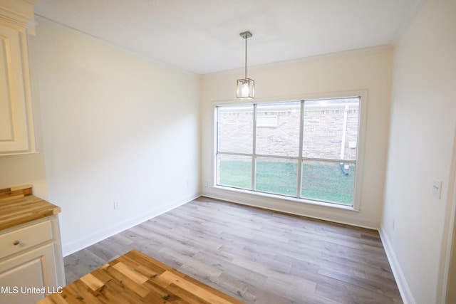 unfurnished dining area featuring crown molding and light hardwood / wood-style flooring