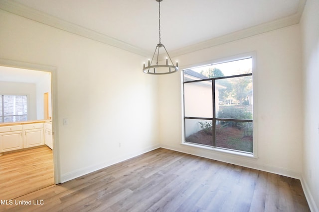 unfurnished dining area with a notable chandelier, light hardwood / wood-style floors, and crown molding