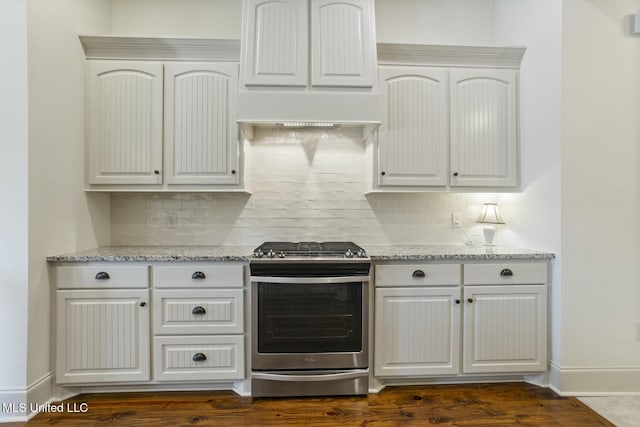 kitchen with backsplash, baseboards, premium range hood, light stone countertops, and stainless steel gas stove