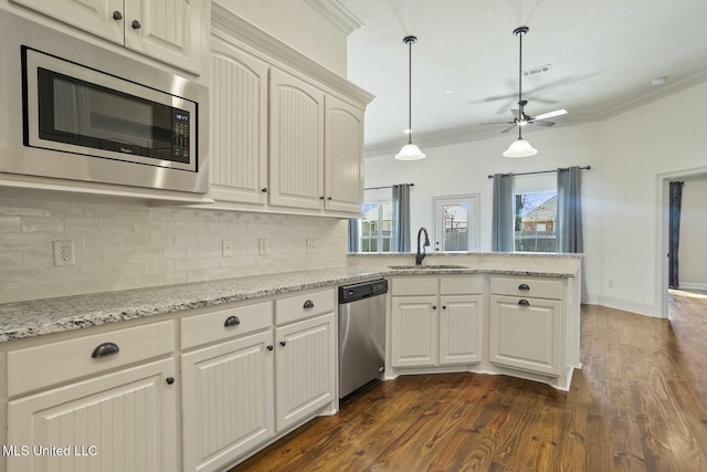 kitchen featuring a sink, a peninsula, crown molding, and stainless steel appliances