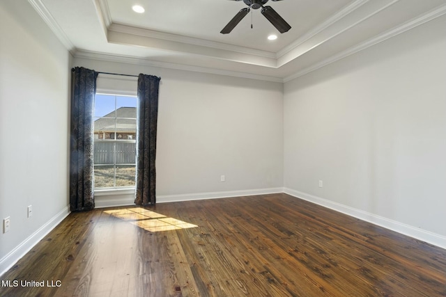 empty room featuring baseboards, dark wood finished floors, a tray ceiling, ornamental molding, and recessed lighting