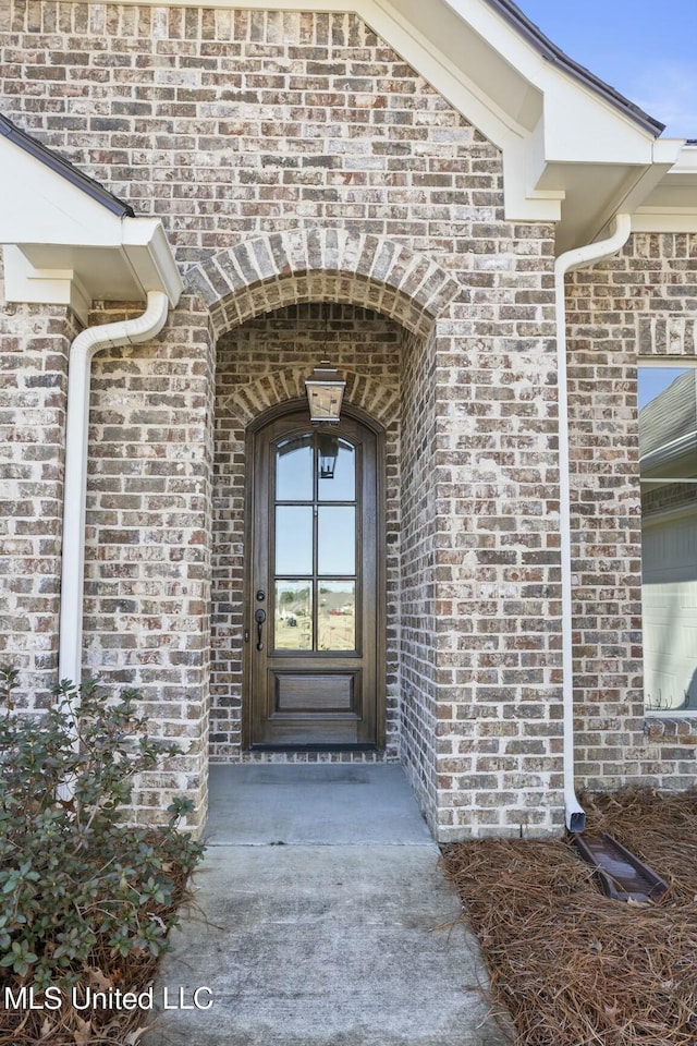 view of exterior entry featuring brick siding