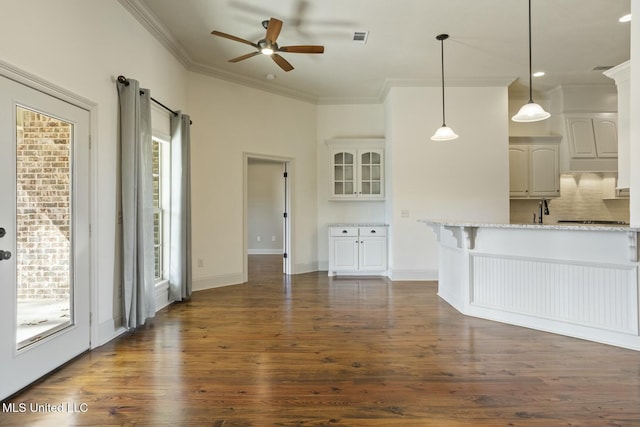 interior space with visible vents, baseboards, dark wood-type flooring, and ornamental molding