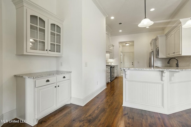 kitchen featuring dark wood finished floors, a peninsula, a sink, stainless steel appliances, and glass insert cabinets