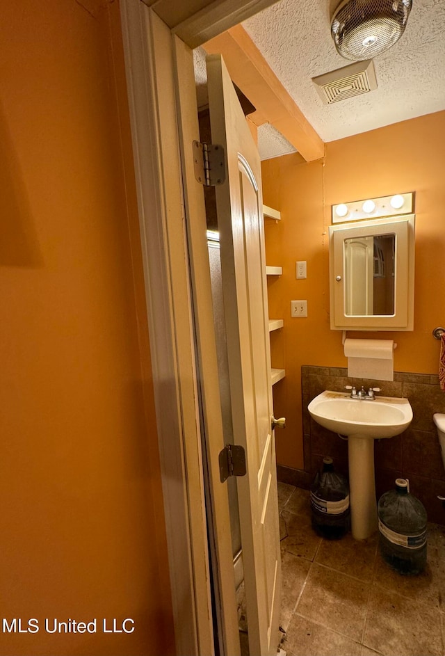 bathroom with a textured ceiling, sink, and tile patterned floors