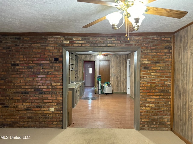 hall featuring ornamental molding, a textured ceiling, wooden walls, and wood-type flooring