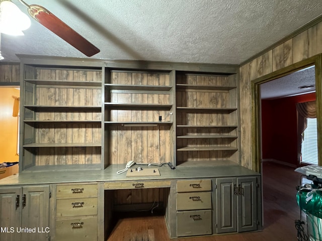 office area featuring wooden walls, dark hardwood / wood-style floors, a textured ceiling, and ceiling fan