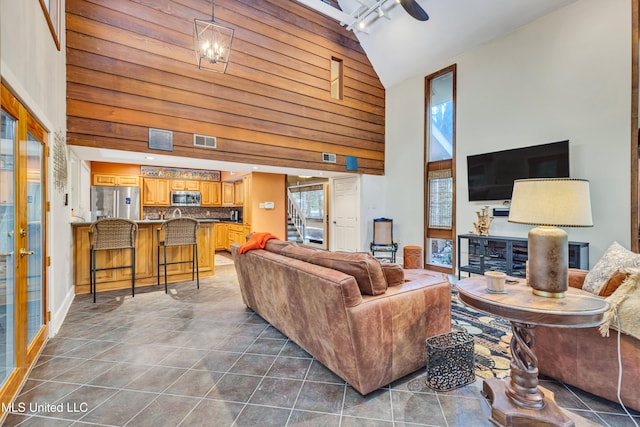 living room featuring dark tile patterned flooring, a notable chandelier, and high vaulted ceiling