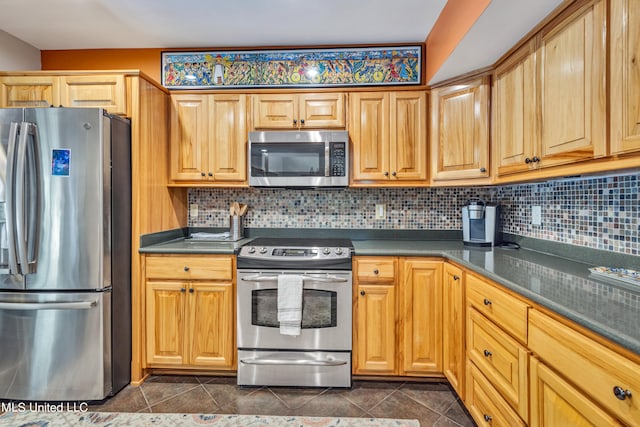 kitchen with dark tile patterned flooring, tasteful backsplash, and appliances with stainless steel finishes