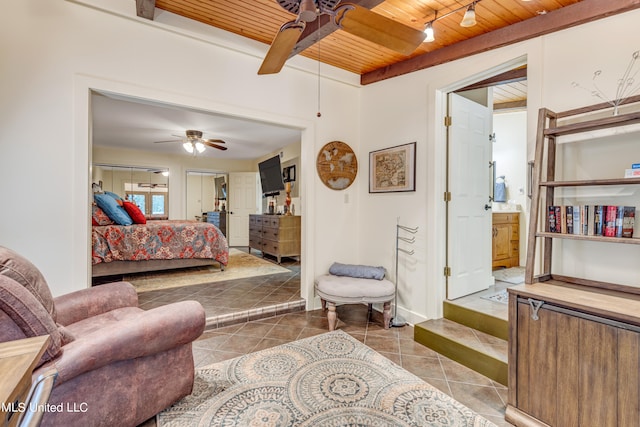 bedroom featuring wood ceiling, tile patterned flooring, ensuite bath, and ceiling fan