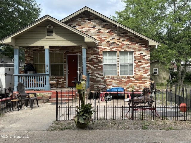 view of front of home with a porch, brick siding, and a fenced front yard