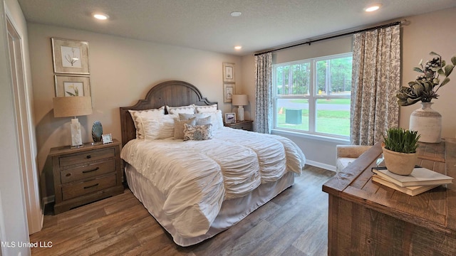 bedroom with dark hardwood / wood-style floors and a textured ceiling