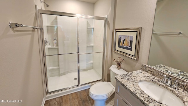 bathroom with toilet, hardwood / wood-style floors, walk in shower, and vanity