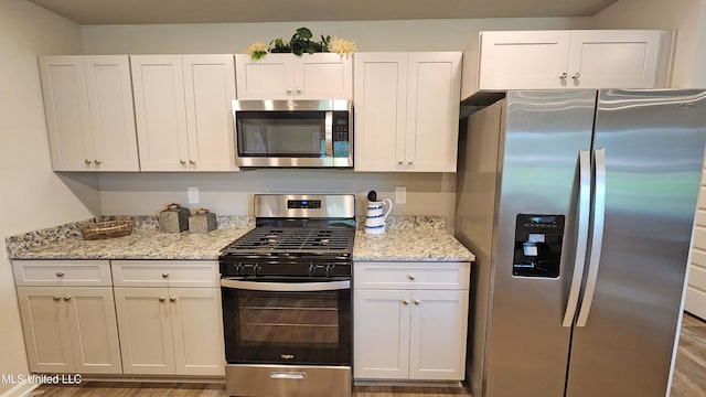 kitchen with white cabinetry, stainless steel appliances, and hardwood / wood-style flooring