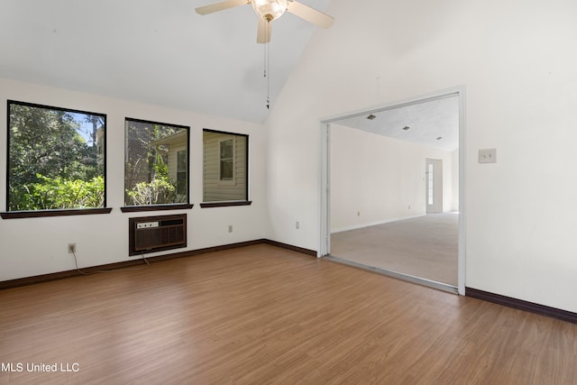 empty room featuring ceiling fan, high vaulted ceiling, wood-type flooring, and a wall unit AC