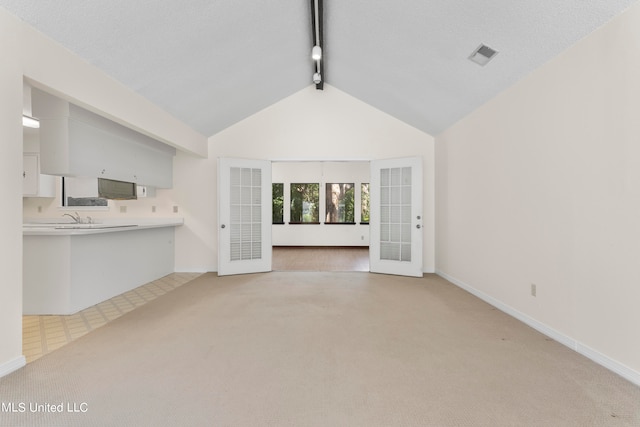 unfurnished living room featuring lofted ceiling with beams, sink, and light colored carpet