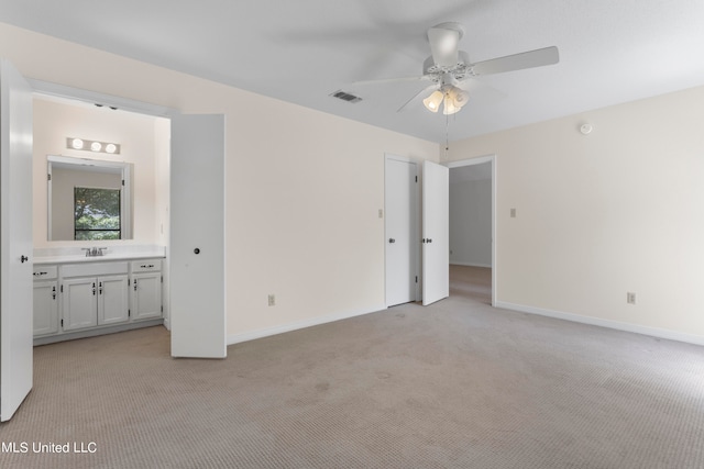 unfurnished bedroom featuring ceiling fan, ensuite bathroom, and light colored carpet