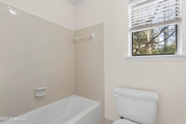 bathroom with toilet and tiled shower / bath combo