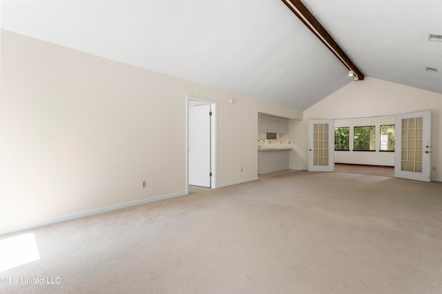 unfurnished living room featuring vaulted ceiling with beams, french doors, and light colored carpet