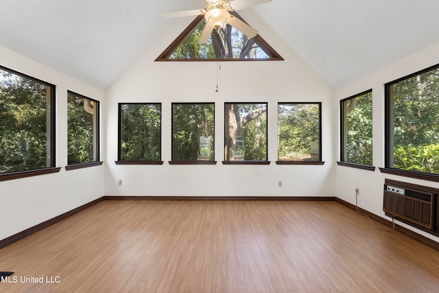 unfurnished sunroom featuring a wall mounted air conditioner, a healthy amount of sunlight, ceiling fan, and vaulted ceiling